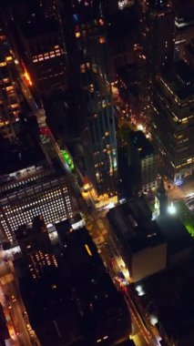 New York 'ta hiç uyumama vakti. Yüksek binaların ve muhteşem gökdelenlerin üzerindeki insansız hava aracı görüntüleri. Dikey video.