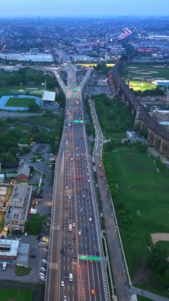 高速高速公路 有大量的交通工具经过 城市上空的无人机镜头 有绿色的公园 河流和体育馆 纽约日落的时候垂直录像 — 图库视频影像