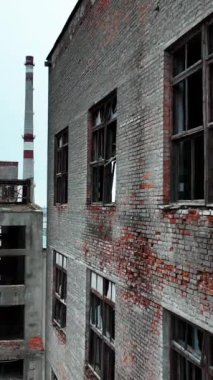 Endüstriyel tesisin yıkılmış ve terk edilmiş bölgesi. Zaman ve doğa ile yok edilmiş eski bir bitkinin binaları. Dikey video.