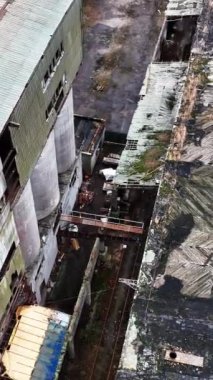 Terk edilmiş eski bir kimya fabrikasının çatısındaki delikler. Topraklar ve binalar çürüyor. Havadan bakış açısı. Dikey video.