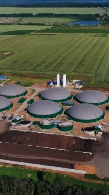 Atık biyoenerji üretimi için sanayi tesisi. Hava perspektifinden organik yakıt tankları. Arkaplanda bol tarım arazileri ve ormanlar var. Dikey video.