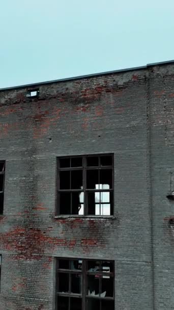 古いレンガ工場の建物 窓が壊れた家に近づいて 中は空っぽ ブルースカイバックドロップ バーティカルビデオ — ストック動画