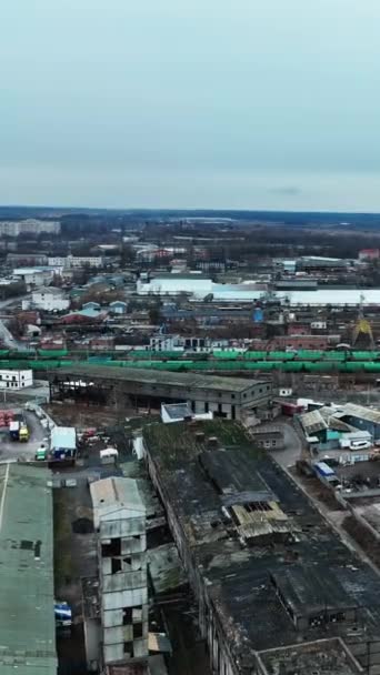 長い間放棄された巨大な工業地帯 鉄道や電車の近くに古い破壊された倉庫の空中観察 背景にある街の景色 バーティカルビデオ — ストック動画