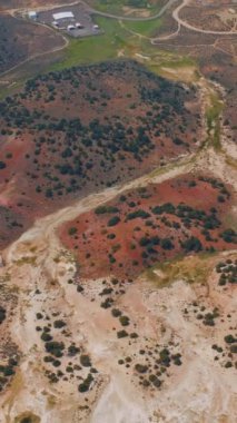 Değişik renklerde kuru ve ıssız araziyi geçen birkaç patika var. Travertine Kaplıcaları 'nın arka planında birkaç ev olan panoraması. Dikey video.