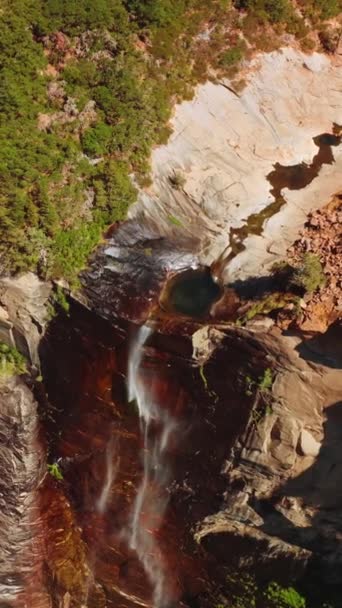美国加利福尼亚州约塞米蒂山上的小瀑布 高高的岩石悬崖上有一条小溪掉了下来 阳光灿烂的日子从顶部拍摄 垂直录像 — 图库视频影像