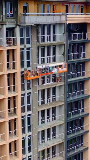 建設中の高層建築 屋外エレベーターの労働者は 多階建ての建物の美しい正面をしています バーティカルビデオ — ストック動画