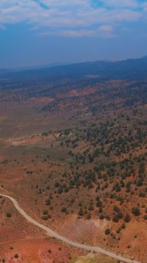 Göl ve dağların arasında kocaman kuru bir vadi. Bulutlu koyu mavi gökyüzü ile kurak arazinin etkileyici manzarası. Hava görüntüsü. Dikey video.