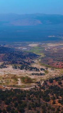 California, ABD 'de sıradışı Travertine Kaplıcaları manzarasının güzel manzarası. Arkaplanda derin mavi sisli dağlar. Hava görüntüsü. Dikey video.