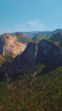 Yosemite Ulusal Parkı 'nda çok güzel kaya oluşumları var. Dağları aşan çam ağacı ormanı. Güneşli bir gün, açık gökyüzü arkaplanı. Dikey video.