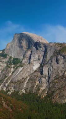 Yosemite Ulusal Parkı, Kaliforniya, ABD 'deki kayalıklara yavaş çekim yaklaşımı. Dağın eteğinde çam ağacı ağacı ağacı yetişiyor. Dikey video.