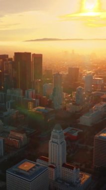 Günbatımında çağdaş Los Angeles 'ın muhteşem manzarası. Arka plandaki güneş ışınlarının parlak ışığında sisli bir ufuk çizgisi. Hava görüntüsü. Dikey video.
