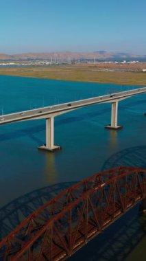 Carquinez Boğazı 'nın mavi suları üzerinde üç komşu köprü. Martinez-Benicia köprüsünde bir sürü araba var. Güneşli, açık bir gün görüntüsü. Dikey video.