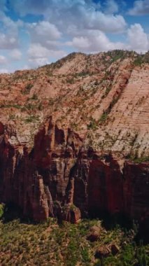 Zion Ulusal Parkı 'ndaki engebeli kayaya yakın uçuyor. Amerika 'nın güzel kanyonları bulutlu mavi gökyüzünün arka planında. Dikey video.