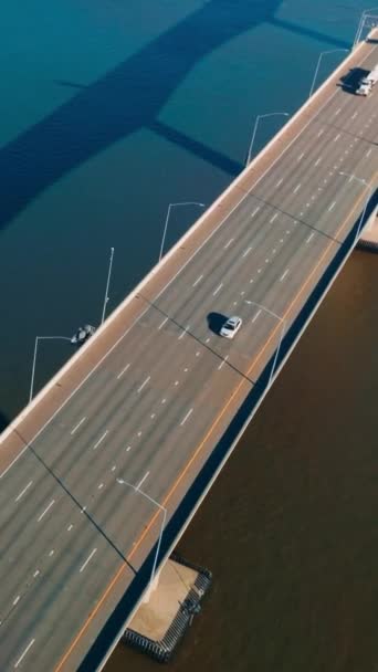 一方通行の多車道を備えた自動車ブリッジ 落ち着いた青い水の上に橋で移動する輸送 トップビュー バーティカルビデオ — ストック動画