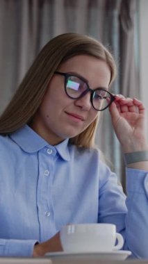 Dizüstü bilgisayarı üzerinde çalışan kadın bir ofis çalışanı. Gözlüklü sarışın kadın şirket ortaklarına mesaj yazıyor. Dikey video.