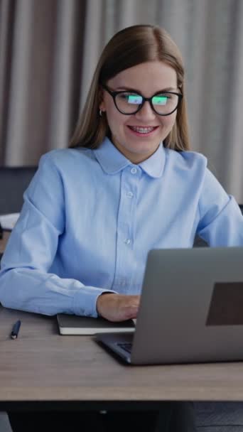 在她的笔记本电脑上工作的女职员 金发女人戴眼镜 给公司合伙人打信 垂直录像 — 图库视频影像
