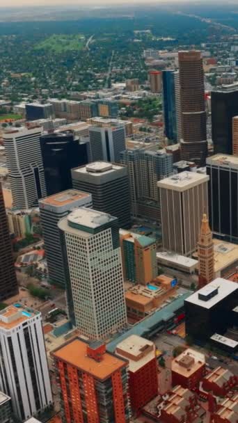 緑の街並みを背景にしたデンバーの高層ビル 昼間の空中視点から美しい都市建築 バーティカルビデオ — ストック動画