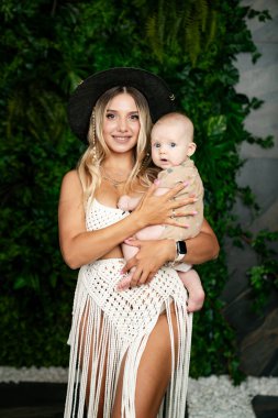 Genç anne bebeğini kollarına alıp gülümsüyor..