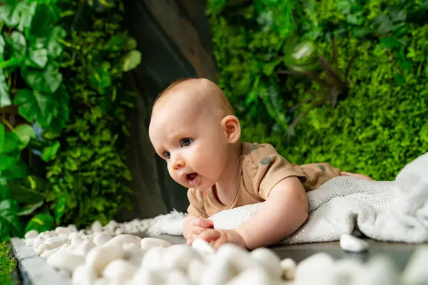 Симпатична Дитина Лежить Ковдрі Зеленій Кімнаті Білими Каменями Зеленими Рослинами — стокове фото