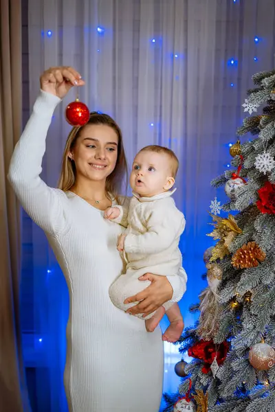 Joven Madre Sostiene Bebé Sus Brazos Decora Árbol Navidad Año — Foto de Stock