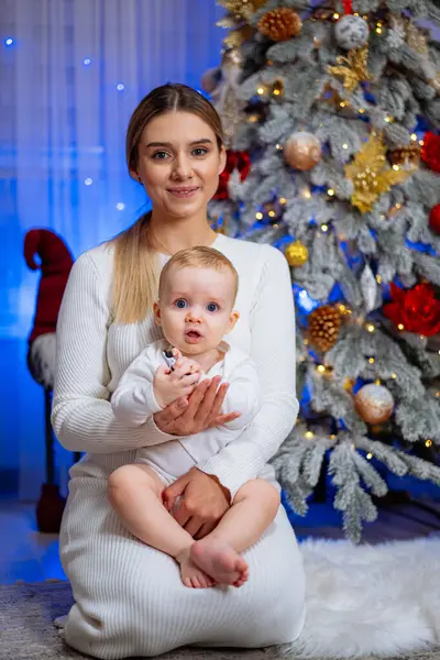 Joven Madre Sostiene Bebé Sus Brazos Cerca Del Árbol Navidad — Foto de Stock
