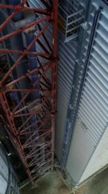 İçinde tüp bulunan metal kahverengi kule bir depo ve depo deposuna bağlı. Tahıl ambarı boyunca inen görüntüler. Üst Manzara. Dikey video