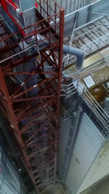Asansör sarnıçlarının yanında metal destekler var. Depo ve tahıl tankı arasında duran kule boyunca iniyoruz. Hava görüntüsü. Dikey video