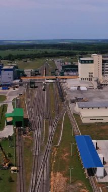 Endüstriyel sanayi bölgesinden geçen kargo trenli demiryolları. Demiryollarının her iki tarafında da asansör tesisi ve ambar konteynırları var. Hava görüntüsü. Dikey video