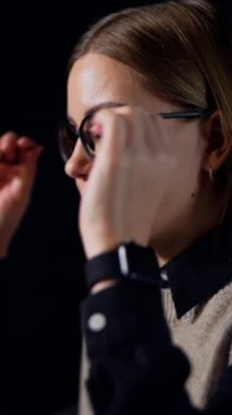 Çekici sarışın kadın gözlüklerini çıkarıyor. Bayan işten kaçmak için şakaklarına masaj yapıyor. Yan görünüm, yakın plan portre. Dikey video