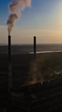 Gün batımında karanlık bir fabrikanın silueti. Üretim havaya zararlı duman salar. Doğa tehlikede. Akşamları nehir kenarındaki sanayi bölgesinde. Dikey video