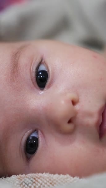 チャーミングな赤ちゃんの顔は定期的に彼の小さな口を開きます お風呂の後 タオルで覆われた素敵な子供の顔 クローズアップ バーティカルビデオ — ストック動画