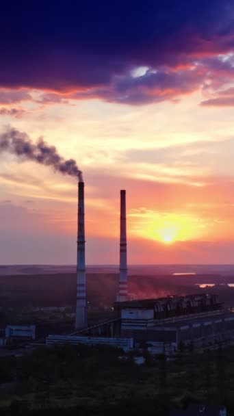 産業は自然を汚染する 日没時の田舎の川付近の化学プラント 夜中に放出された産業用パイプからの煙 バーティカルビデオ — ストック動画
