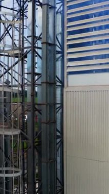 Modern endüstriyel fabrikanın dışı. Depodan içeri beyaz duman doluyor. Yakın plan. Çevreyi kirletiyor. Kamera yükseliyor. Dikey video
