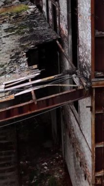 Yıkılmış bina. Kırık camları ve duvarlarında delikleri olan eski bir mimari. Askeri harekat sırasında hasar gören işletmenin dış cephesi. Yakın plan. Dikey video