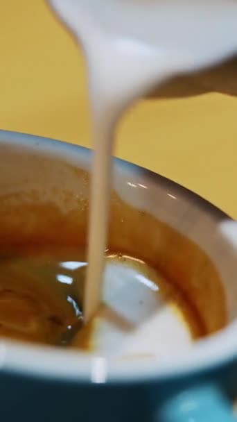 Barista fabrication de café latte art. Forme de coeur sur le café dans une tasse. Faire du latte en versant lentement du lait dans une tasse bleue. Gros plan. Vidéo verticale