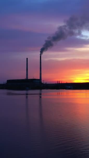 靠近水的工业厂房 在美丽的夜晚大自然中 来自工厂的烟雾 日落时的制造业概况 摄像头向前移动 垂直录像 — 图库视频影像