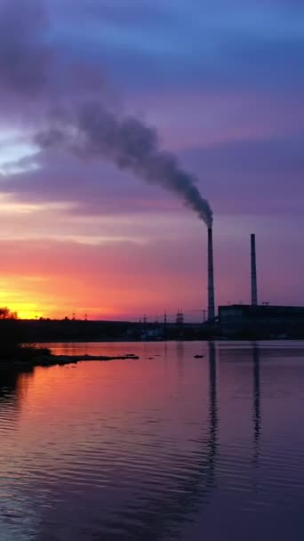 河流附近有烟的工业管道 日落时 工厂向空气中排放有害气体 在工业背景下飞越晚水 垂直录像 — 图库视频影像