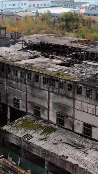 古い放棄された工場 軍事活動の後 屋根に多くの穴がある破壊された建物の外観 屋外で被害を受けた建物 空からの眺め バーティカルビデオ — ストック動画