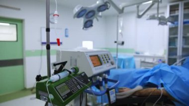 Ameliyat sırasında modern tıbbi ekipmanlar ameliyathanede çalışıyor. Ameliyat masasında yatan bir hastaya bağlı çeşitli apparatüslerden tüpler..