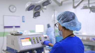 Kadın bir hemşirenin aletin sapını çevirmesi. Cerrahi odasındaki cihazın gerekli parametrelerini ayarlayan sağlık görevlisi.