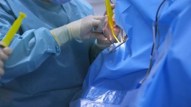 Profesyonel bir cerrahın eldivenli elleri dikkatlice enstrüman takar. Maskeli erkek doktor kafasına cihaz gözlüğü takıyor..
