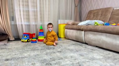 Güzel, aktif bir çocuk hızla odada emekliyor. Emzik takan çocuk merdivenlere doğru yaklaşır..