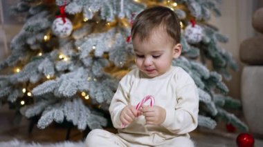 Beyaz tişörtlü beyaz çocuk elinde baston şeker tutuyor. Çocuk şekeri kırıyor ve yere atıyor..