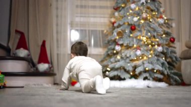 Odanın etrafında sürünen beyaz, şirin bir çocuk. Bebek merdivenlere Noel süslemeleriyle yaklaşıyor. Kapat..