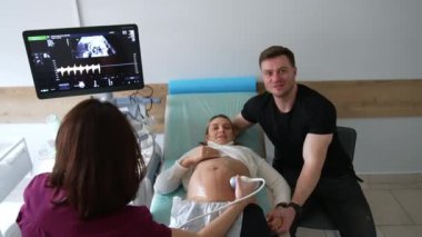 Doktor muayenesinde hamile çocuğuna bakan bir koca. Doktor annemi görmek için ultrason yapar..