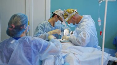 Modern hastanede tiroid üzerinde operasyonel prosedür. Ameliyatı komik şapkalı doktorlar yapar. Yardımcı hemşire aletleri hazırlar..