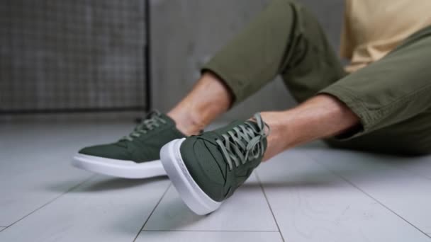 Αρσενικό Μοντέλο Κάθεται Στο Πάτωμα Μοντέρνα Παπούτσια Του Στο Μπροστινό — Αρχείο Βίντεο