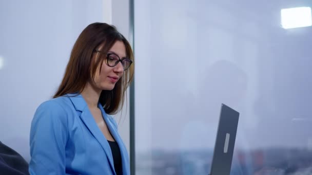 穿着蓝色夹克的黑发女士在电脑上工作 女人坐在柔软的椅子上在笔记本电脑上打字 低角度视图 — 图库视频影像
