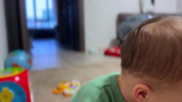 可爱的白人小孩高高地抬头看着 嘴里含着一个手指 可爱的男孩把一个玩具放在近旁 — 图库视频影像