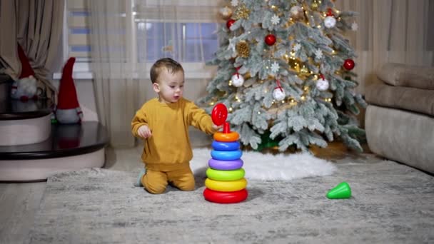 Schöner Kleiner Junge Orangefarbenem Sportanzug Baut Eine Spielzeugpyramide Weihnachtlich Dekorierten — Stockvideo